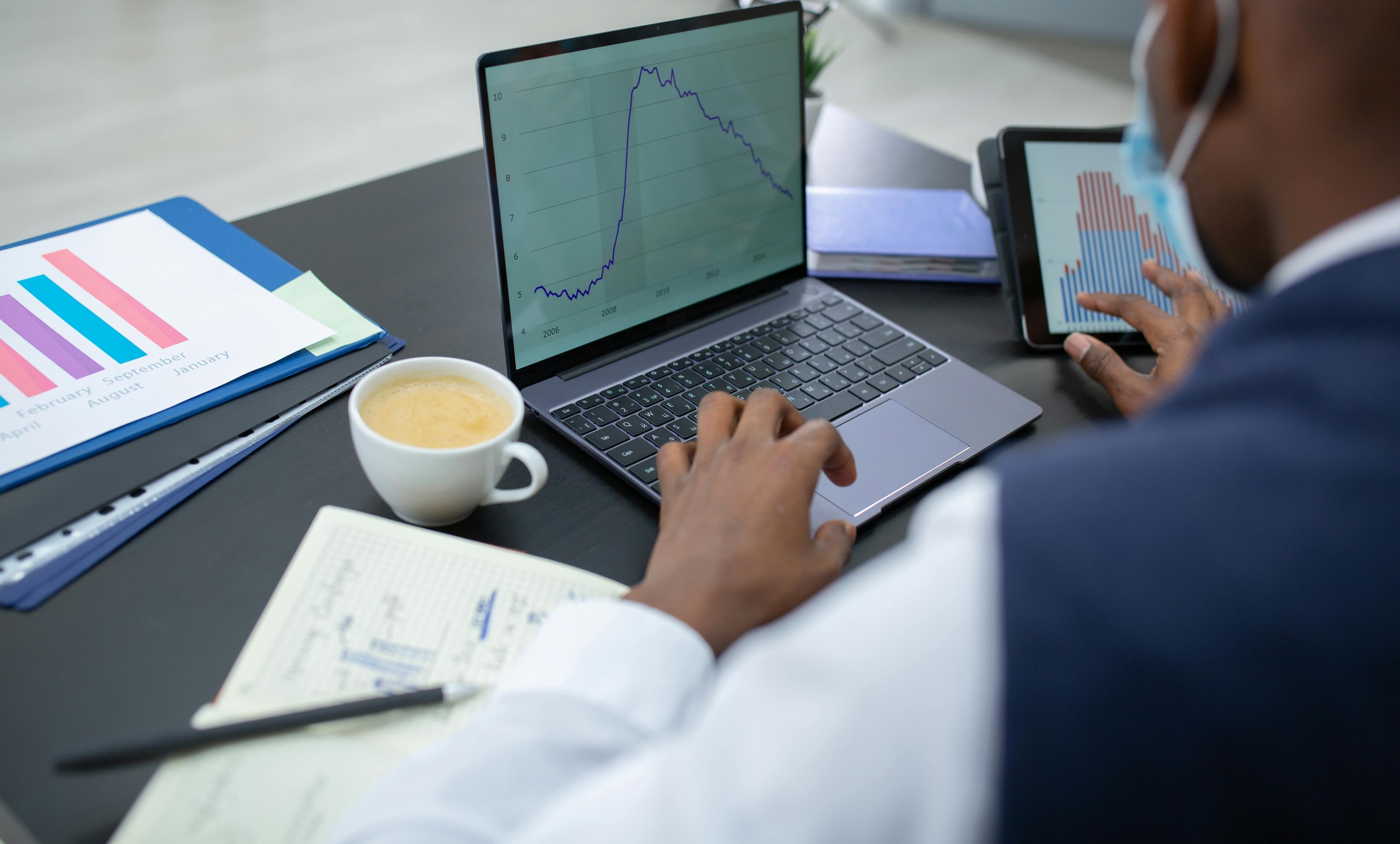 A professional reviewing analytics dashboards on a laptop and tablet.
